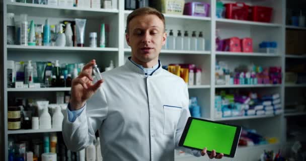 Apotheker, der ein digitales Tablet mit grünem Bildschirm in der Apotheke hält, empfiehlt die Anwendung. Männerporträt — Stockvideo