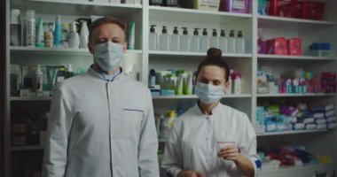 Eczaneden iki adam ve kadın eczanede maskeli, virüsten korunuyorlar. İlaç şirketleri maskelerini çıkartıp temiz hava soluyor..