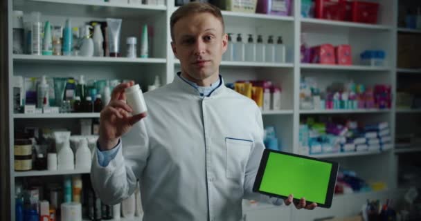 Farmacêutico masculino segurando um comprimido digital com uma tela verde em um químico, recomenda para uso medicina. Retrato masculino — Vídeo de Stock