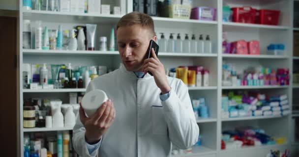 Un farmacéutico de una farmacia aconseja a un cliente por teléfono. Llamada telefónica. — Vídeo de stock