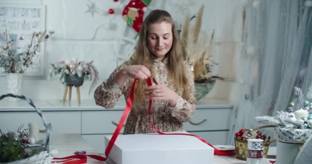 一位年轻的女推销员在花店里把圣诞花圈装进了一个盒子里。礼品包装 — 图库视频影像