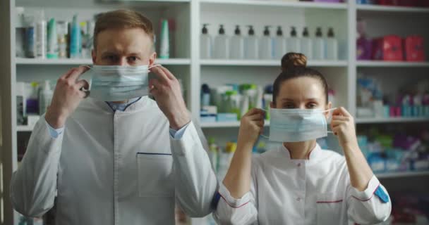 Mužské a ženské lékárnice s ochrannou maskou na tvářích pracující v lékárně. Ukazují palce nahoru..