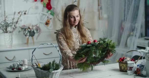 Jeune femme fait une couronne de Noël et décore avec des jouets. Travail manuel. — Video