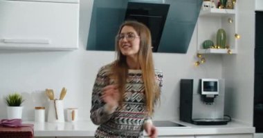 Mutlu kadın hediyesini yakalar. Ve elinde hediyelerle dans ediyor. Mutfağın arka planına karşı..