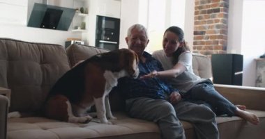 Emekli bir adam, kızı ve av köpeğiyle kanepede oturmuş konuşuyor. Aile Birlikte Zaman Geçiriyor