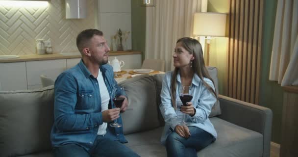 Casal jovem marido e mulher passam tempo juntos em casa na cozinha, bebendo vinho tinto e conversando. — Vídeo de Stock