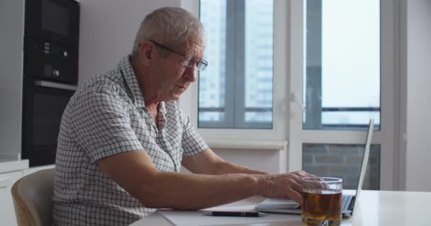 Fatigué Homme âgé avec des lunettes travaille sur un ordinateur portable à la maison, enlève ses lunettes et fait un massage facial de la fatigue. Portrait d'un homme. — Video