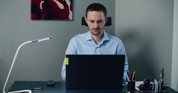 Han sitter på kontoret och jobbar på laptop. Affärsman tittar på dataskärm medan du arbetar på kontoret. — Stockvideo