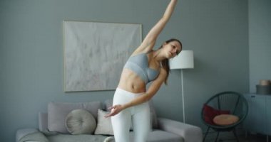 Genç sarışın kadın evde yoga yapıyor, ısınmaya başlıyor. Evde egzersiz yap..