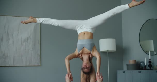 Una joven pareja caucásica de hombres y mujeres practicando yoga acrobático a domicilio. Están en la pose STAR. — Vídeo de stock