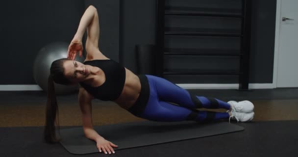 Giovane donna sportiva è impegnata in palestra. Donna che fa esercizi mentre sdraiato sul tappeto in casa. — Video Stock
