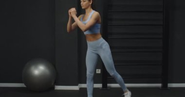 Genç, zayıf sporcu kadın çömelme egzersizleri yapıyor, vücudun alt bacakları üzerinde çalışıyor ve uygulamalı kaslar ideal vücut şeklini oluşturuyor, kaslarını zorlayan atletik kızları tanımlıyor. 
