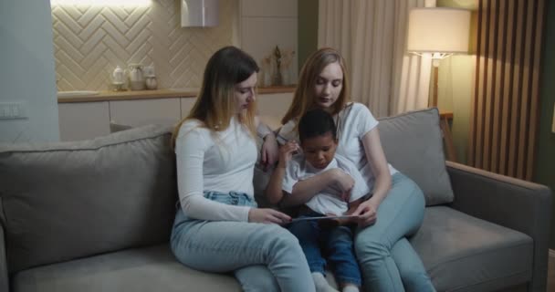 Madre e zia Europei aiutano il loro piccolo figlio afroamericano a disegnare. Famiglia internazionale — Video Stock