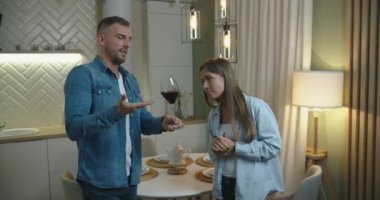 Aşık genç bir çift ev mutfağında kırmızı şarap içiyor. Genç çift kırmızı şarap tadıyor..