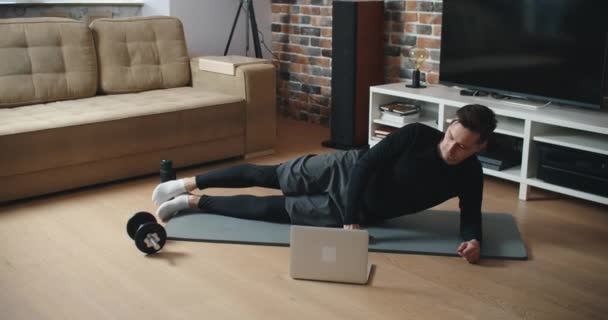 O teu treinador pessoal. Instrutor de fitness masculino mostrando exercícios durante o streaming, transmitindo vídeo lição sobre treinamento em casa usando laptop. Esporte, conceito de ginásio online. — Vídeo de Stock