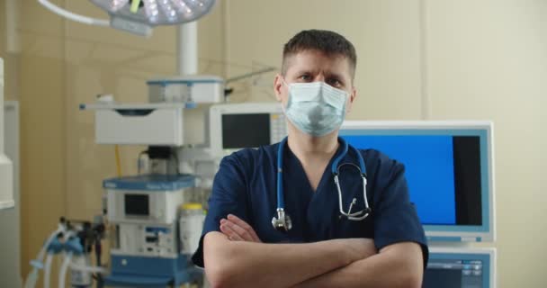 Widok z przodu zbliżenie białego chirurga męskiego pracownika służby zdrowia w szpitalu zakładającego maskę chirurgiczną.Pracownicy służby zdrowia w Coronavirus Covid19 pandemia — Wideo stockowe