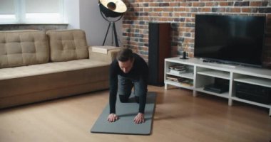 Evde antrenman. Sportif adam yoga yaparken çevrimiçi özel ders izliyor, oturma odasında egzersiz yapıyor, boş yer var.