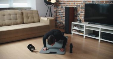 Evde antrenman. Sportif adam yoga yaparken çevrimiçi özel ders izliyor, oturma odasında egzersiz yapıyor, boş yer var.