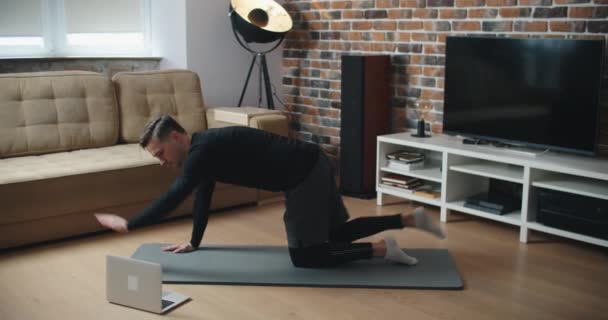 Тренировка дома. Спортивный человек делает доску для йоги во время просмотра онлайн-учебника по мобильному телефону, упражнения в гостиной, свободное пространство — стоковое видео