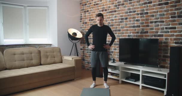 Otthon edzek. Sportos férfi csinál jóga deszka, miközben néz online bemutató a mobil, gyakorló a nappaliban, szabad hely — Stock videók