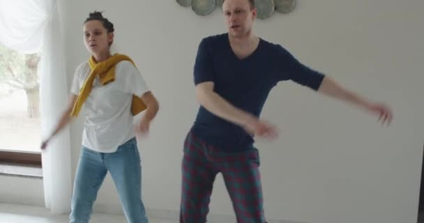 En mand og en kvinde danser modsat et tv, parodi og gentage, hvad de viser på tv – Stock-video
