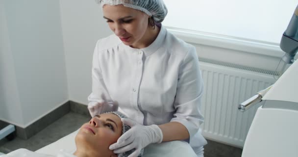 Cosmetologia. Closeup de rosto feminino ter tratamento facial no salão de beleza. Procedimentos cosméticos na clínica de spa. — Vídeo de Stock