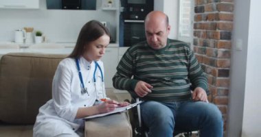 Evde konuşurken tekerlekli sandalyedeki hastaya bilgi veren genç bir hemşire. Salgın ve virüs kavramı