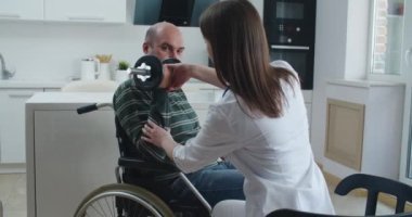 Evde konuşurken tekerlekli sandalyedeki hastaya bilgi veren genç bir hemşire. Salgın ve virüs kavramı