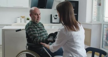 Evde konuşurken tekerlekli sandalyedeki hastaya bilgi veren genç bir hemşire. Salgın ve virüs kavramı