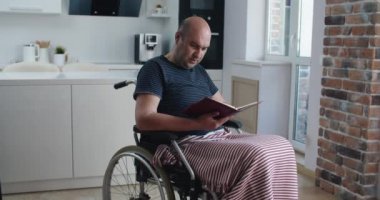 Mutlu engelli adam tekerlekli sandalyeye otur ve kitabı tut, gülümseyen yaşlı adam keyfini çıkar. 