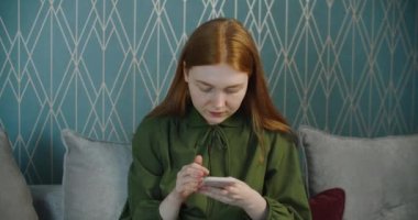 Genç, mutlu, kızıl saçlı, akıllı telefonlu bir kadın. Zafer ve sevinç. Duygusal kadın zaferle sevinir..