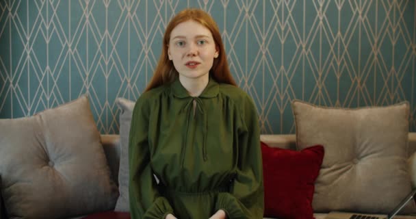 赤い髪の悲しい若い女性は、ビデオリンクを介して通信します。悲しい知らせ. — ストック動画