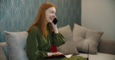 Mutlu genç kadın evde cep telefonuyla konuşarak eğleniyor.