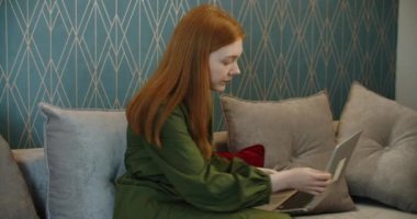 Evde cep telefonuyla konuşan üzgün genç bir kadın.