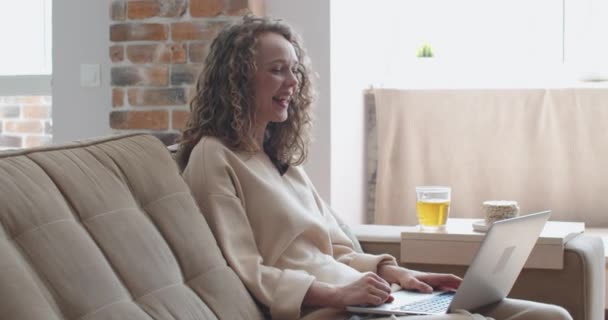 Junge fröhliche Frau mit lockigem Haar kommuniziert per Videokommunikation mit Freunden — Stockvideo