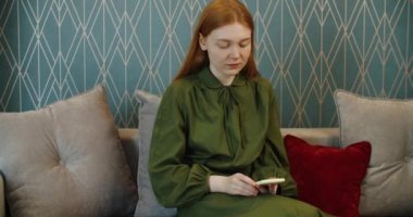 Kızıl saçlı genç mutlu kadın video iletişimiyle arkadaşlarıyla iletişim kuruyor..