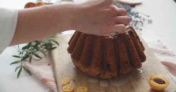 Cupcakes voorbereiding - hand houden cupcake, kumquat, geruite servet, witte achtergrond. Close-up — Stockvideo