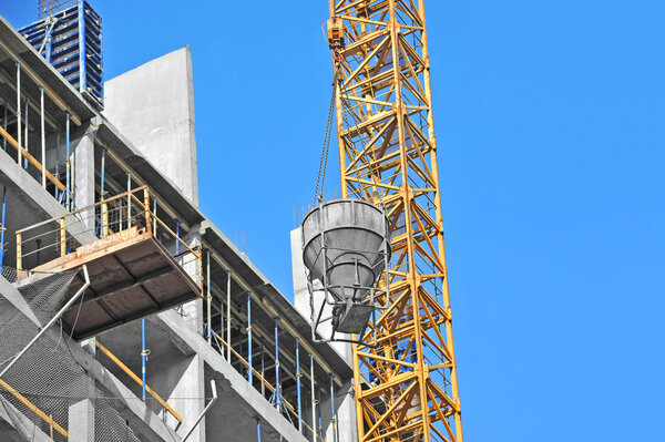 Crane lifting concrete mixer container against blue sky