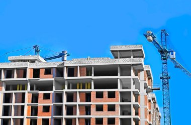 Mavi gökyüzüne karşı vinç ve inşaat alanı