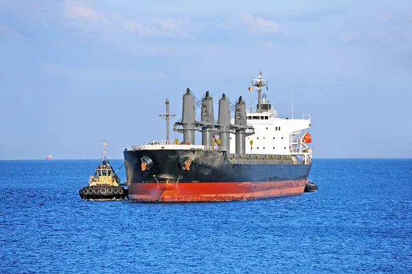 Буксир помогает грузовому судну — стоковое фото