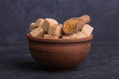 Kil kasede kahverengi kamış şeker küpleri ve tahta kaşık.