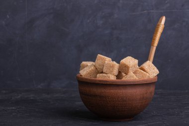 Kil kasede kahverengi kamış şeker küpleri ve tahta kaşık.