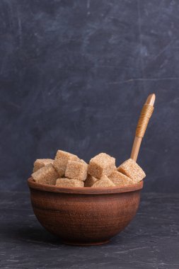 Kil kasede kahverengi kamış şeker küpleri ve tahta kaşık.