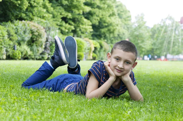 Garçon allongé sur l'herbe dans le parc — Photo