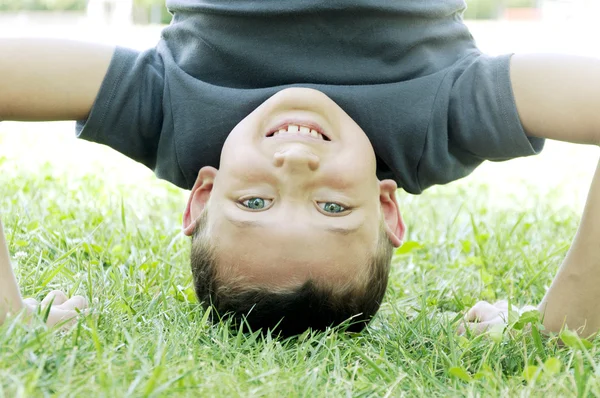 Gelukkige jongen ondersteboven op het gras — Stockfoto