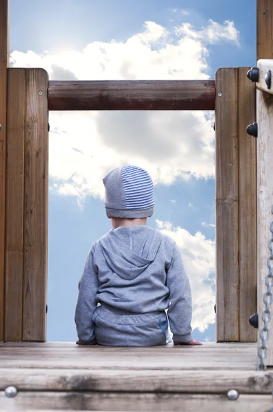 Мальчик сидит и смотрит на небо — стоковое фото