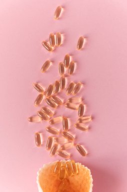 Pembe arka planda omega-3 kapsüllü waffle konisi. Yaklaş, üstten bak. Sağlık, vitamin, bağışıklık kavramı