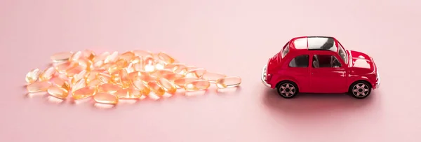 Pequeno Carro Vermelho Está Carregando Cápsulas Óleo Peixe Fundo Rosa — Fotografia de Stock