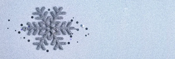 A silver-colored snowflake on a silver background. Shiny background with glitter