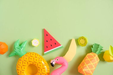 Yeşil zemin üzerinde şişme elementler bulunan kağıttan yapılmış egzotik meyveler. Yaz kavramı. Tatil